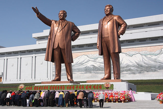 Người dân Bắc Triều Tiên đang cúi đầu trước tượng của ông Kim Il-sung (trái) và ông Kim Jong-il. (Ảnh: wiki)