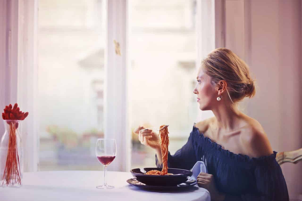 woman sitting on chair while eating pasta dish 1456262 image